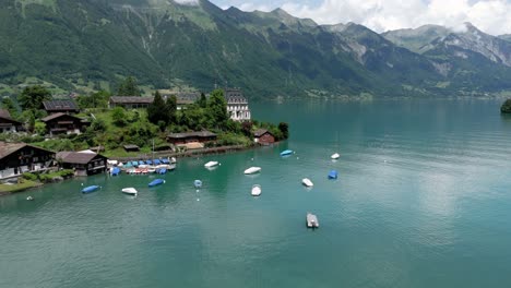 flying to castle seeburg revealing the view of the turquoise lake brienzersee iseltwald surrounded by the alpmointains on a sunny summer day in switzerland near interlaken
