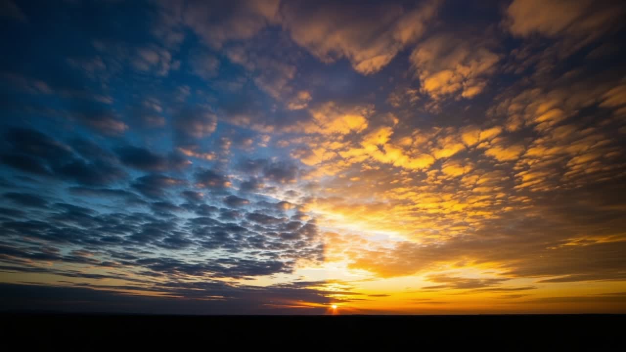 A Stunning Showcase of Nature's Masterpiece: The Transition from Day to Night as the Sun Sets Beneath a Colorful Sky Full of Clouds
