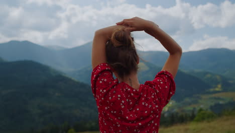 woman standing mountains scenery closeup back view. girl raising hands over head