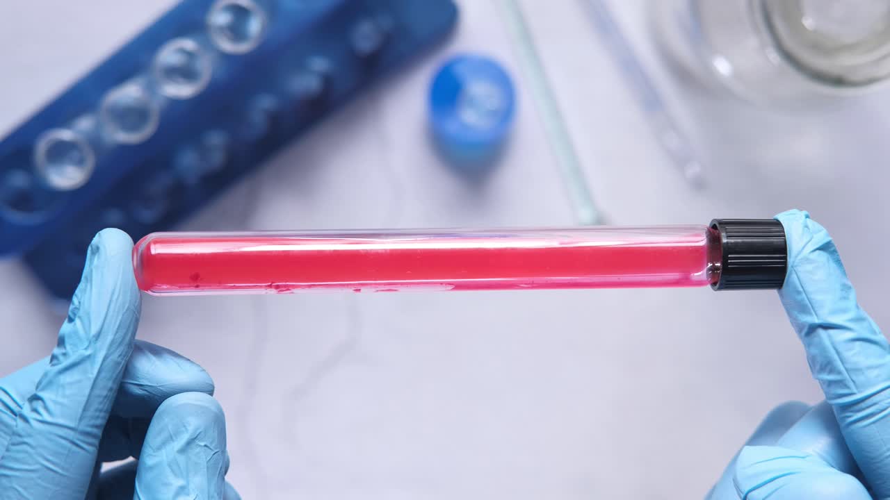 Scientist holding a test tube with a red liquid