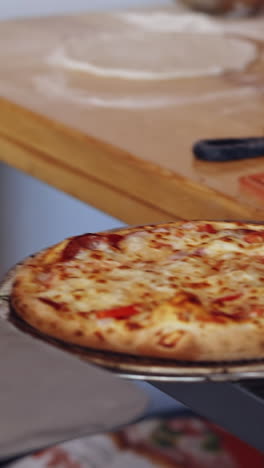 hot delicious pizza. pizzeria master takes out ready pizza from the oven. chef is pulling out fresh pizza with a special pizza spatula in the kitchen. vertical video