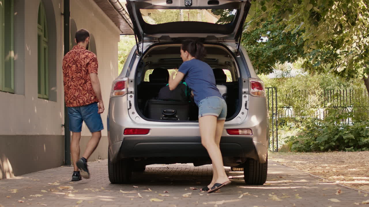Couple packing luggage into car for travel
