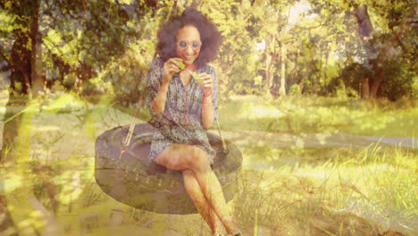 Woman-sitting-on-a-tire-swing-blowing-bubbles