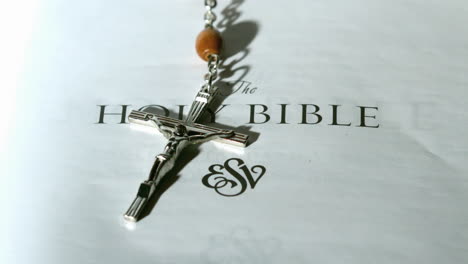 rosary beads falling onto first page of bible