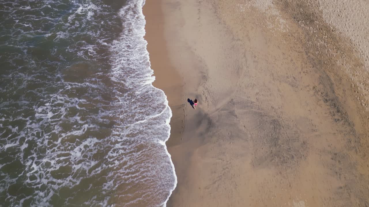Una donna cammina lungo una spiaggia vista da un drone aereo dall'alto