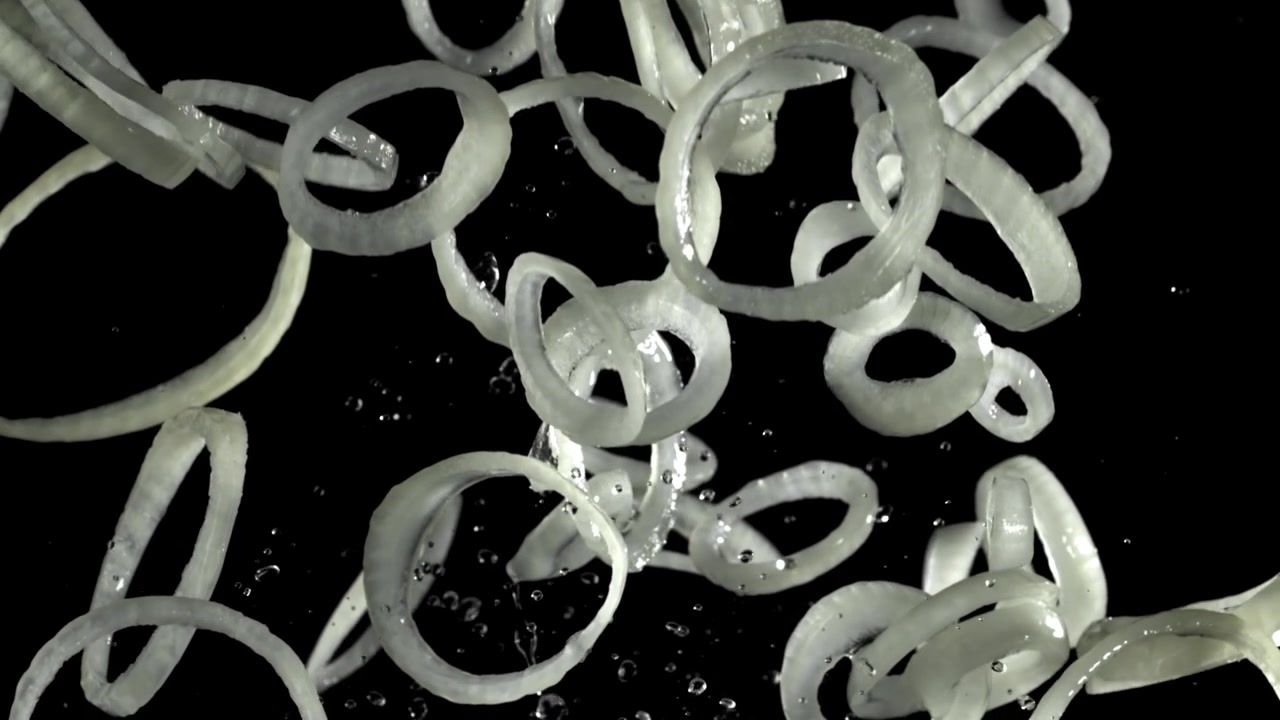 Cincin Bawang Iris Segar Melayang dalam Gerak Lambat dengan Latar Belakang Hitam