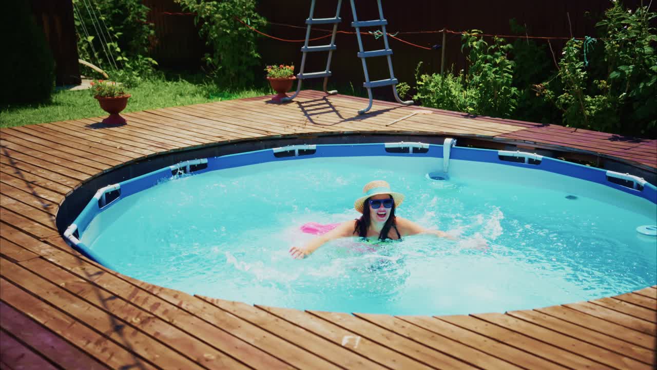 Woman enjoying a refreshing swim in a circular pool surrounded by lush greenery and wooden deck