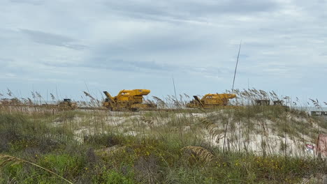 View over dunes of construction equipment working beach replenishment