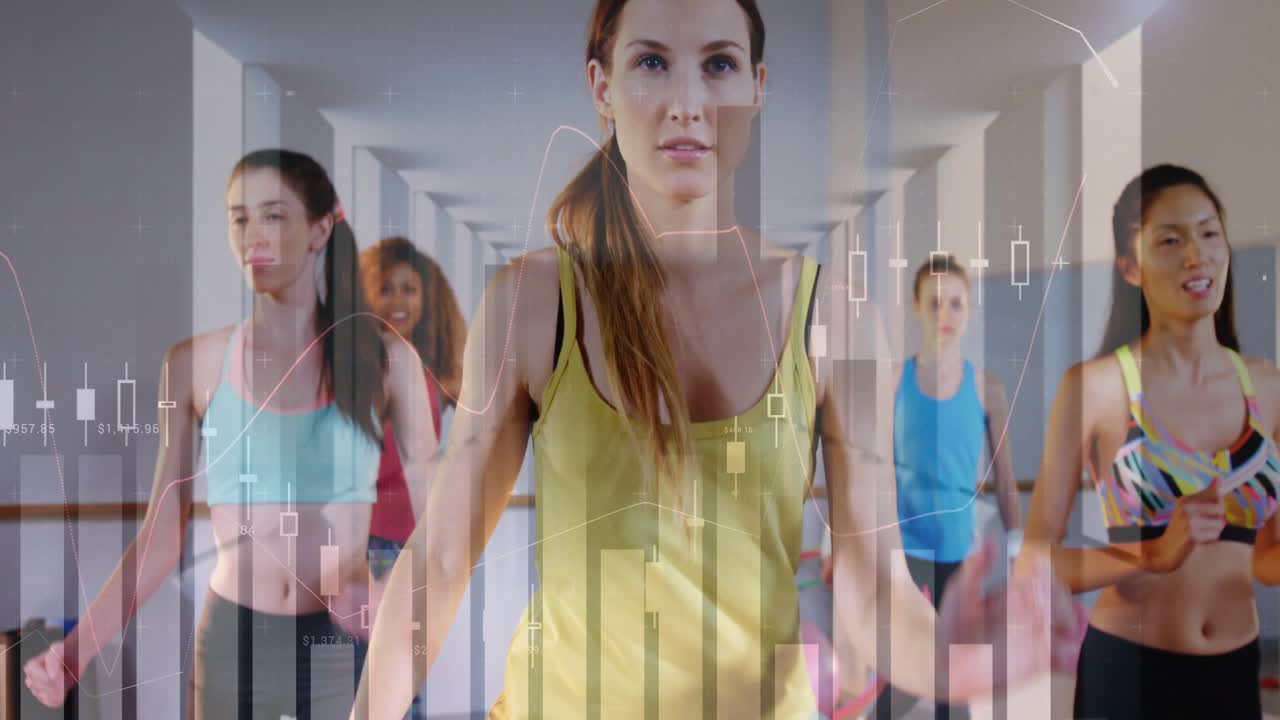Istruttore principale che solleva le ginocchia, esortando la classe a sincronizzarsi per il cardio, la telecamera zooma, grafici finanziari in sovrapposizione.