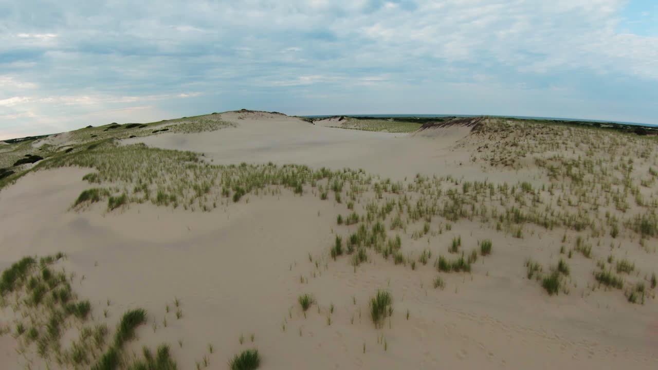снимок с беспилотного летательного аппарата fpv живописных бесплодных троп, песчаных дюн и крутых склонов с мелкой кустарниковой листвой, расположенных на тропе дюнных хижин в провинстауне, кейп-код, штат массачусетс