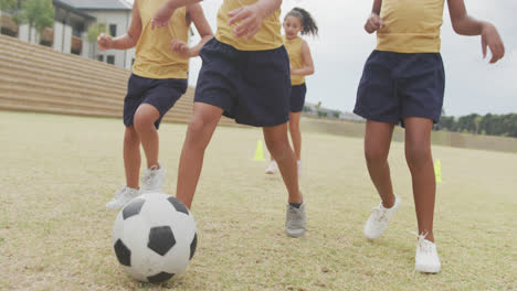 video of legs of diverse girls playing soccer in front of school