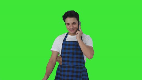 Happy-Indian-cook-making-food-while-talking-on-phone-Green-screen