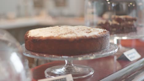 pastel orgánico con cobertura de almendras en un puesto de comida de vidrio mesa de postres con más pasteles además de en un mostrador en un café