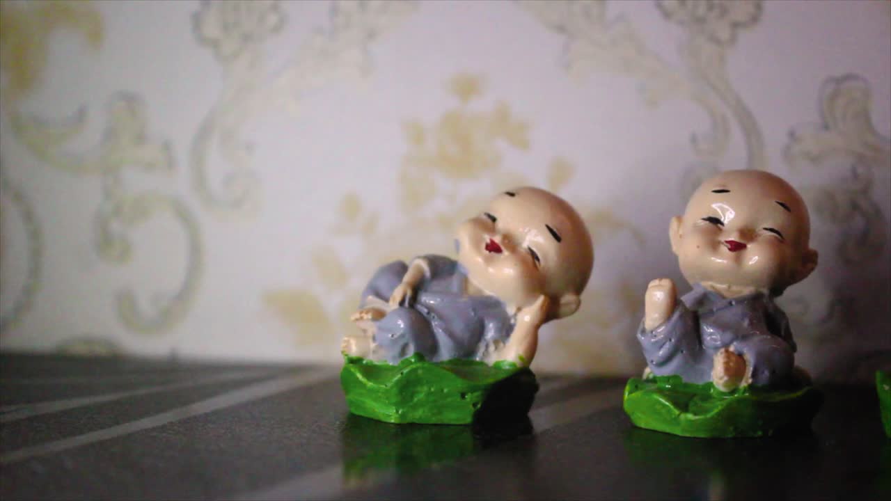 Vista aproximada de quatro estatuetas alegres de monges em poses adoráveis. Símbolo perfeito de paz, Zen e serenidade. Ótimo para temas espirituais, de meditação, decoração e bem-estar.