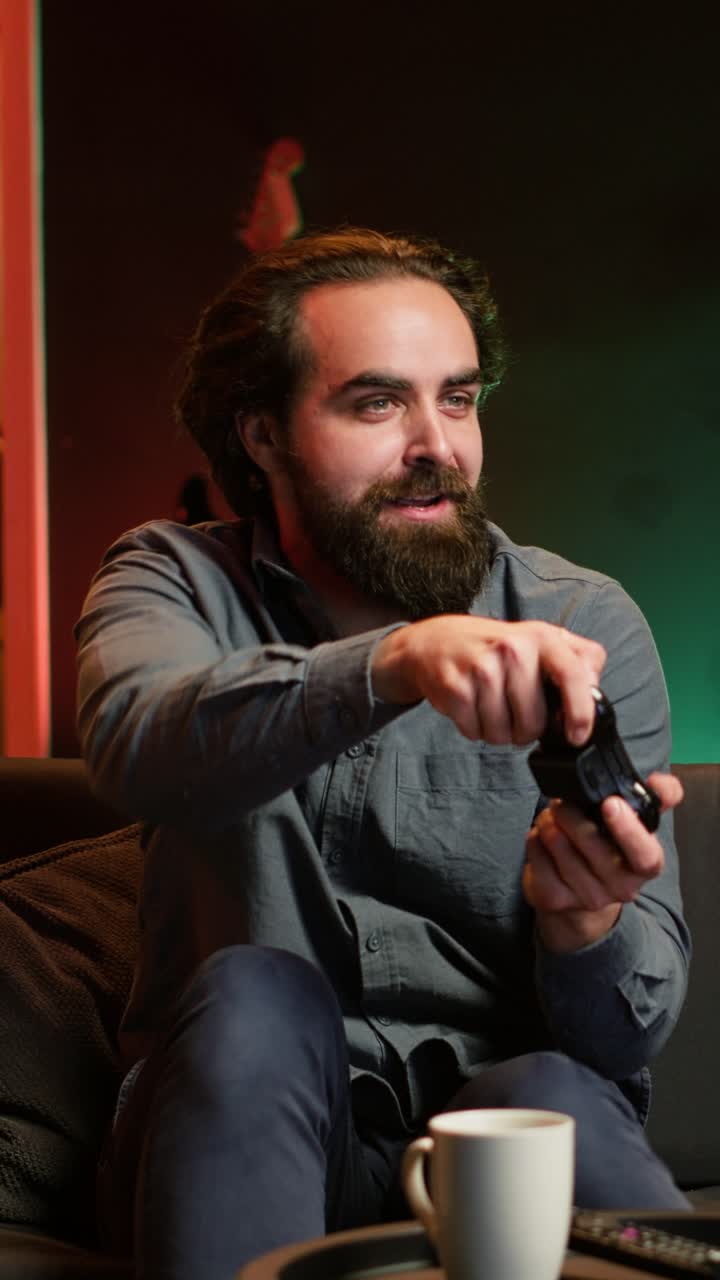 Vertical video Happy man playing videogame in neon illuminated home, holding controller