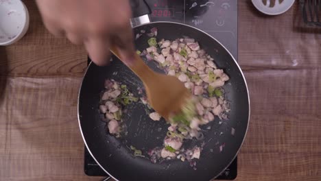 adding fresh scallion to frying chicken. top view