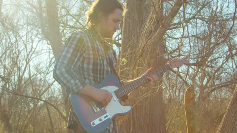 a guitarist plays his electric guitar in nature with the bright sun shining behind him, casting a warm glow. the scene captures the fusion of music and nature.