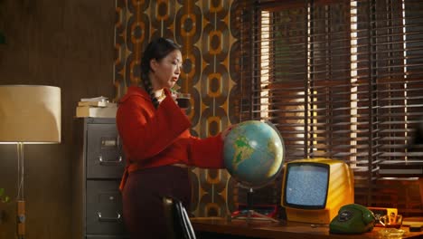 woman drinking coffee and looking at a globe in a retro office