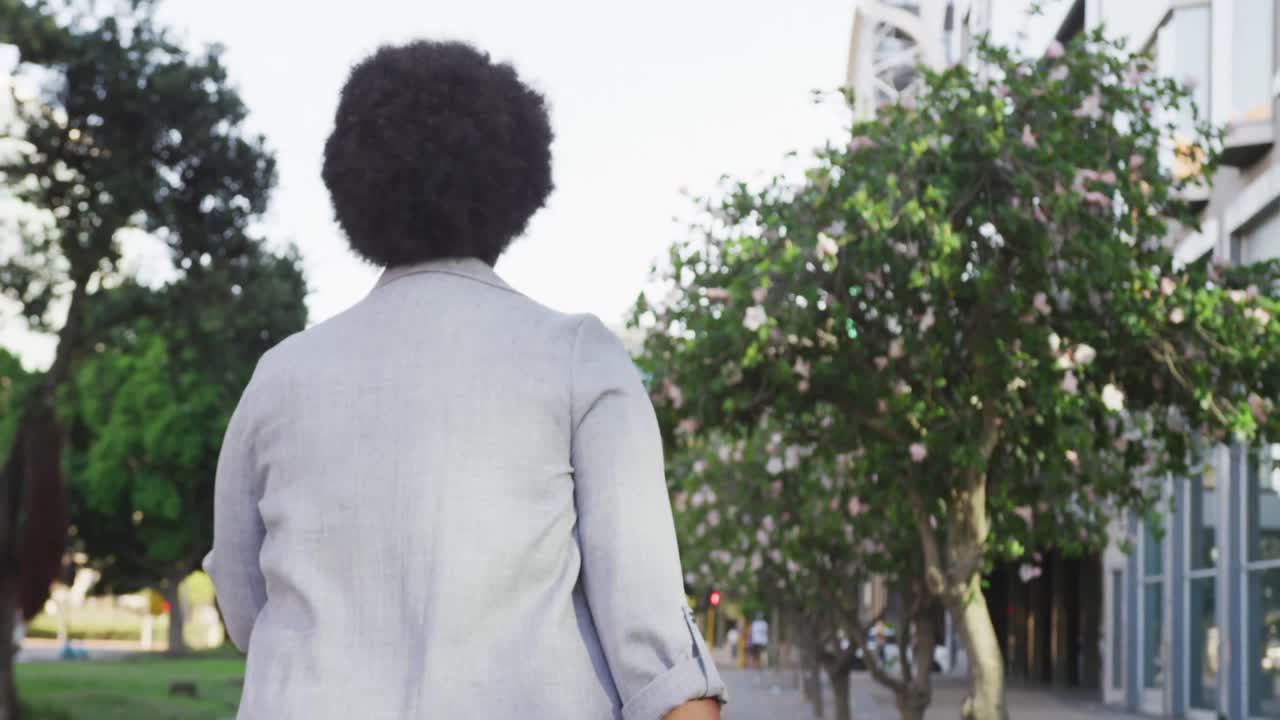 Plus size biracial woman walking with luggage in city