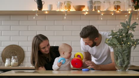 madre y padre con un bebé en la habitación abrazándose sonriendo felices.
