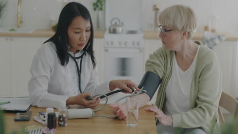doctor checking blood pressure of elderly patient at home