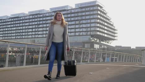 Stylish-young-female-tourist-explores-the-city-with-her-suitcase-in-the-morning-sun