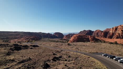 drone shot tracking triathletes along a winding road through snow canyon, utah, highlighting the stunning red rock formations, desert landscape, and natural beauty of the canyon.