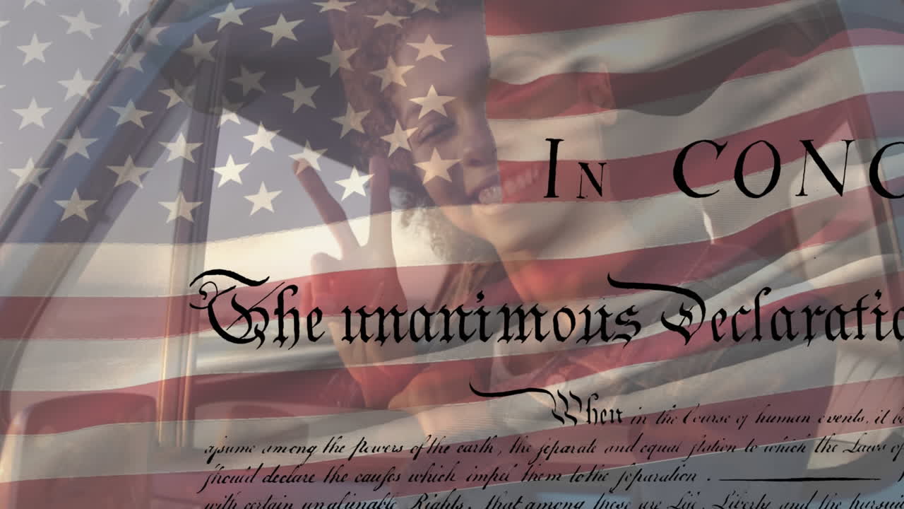 Young biracial woman smiling in car with US flag waving and independence declaration foreground