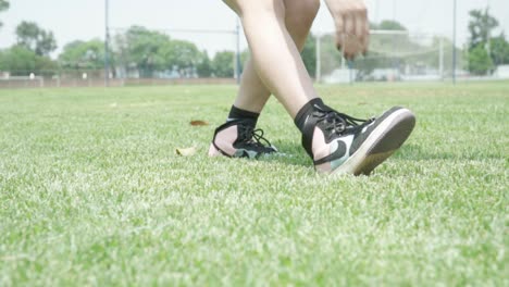 woman stretching legs on grass field