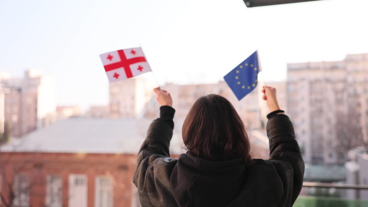 Žena držící gruzínskou vlajku a vlajku EU