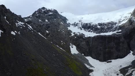 Relaxing-descent-from-mountain-peak-to-glacier-valley-in-Fiordland,-New-Zealand,-South-Island,-pan-right-aerial