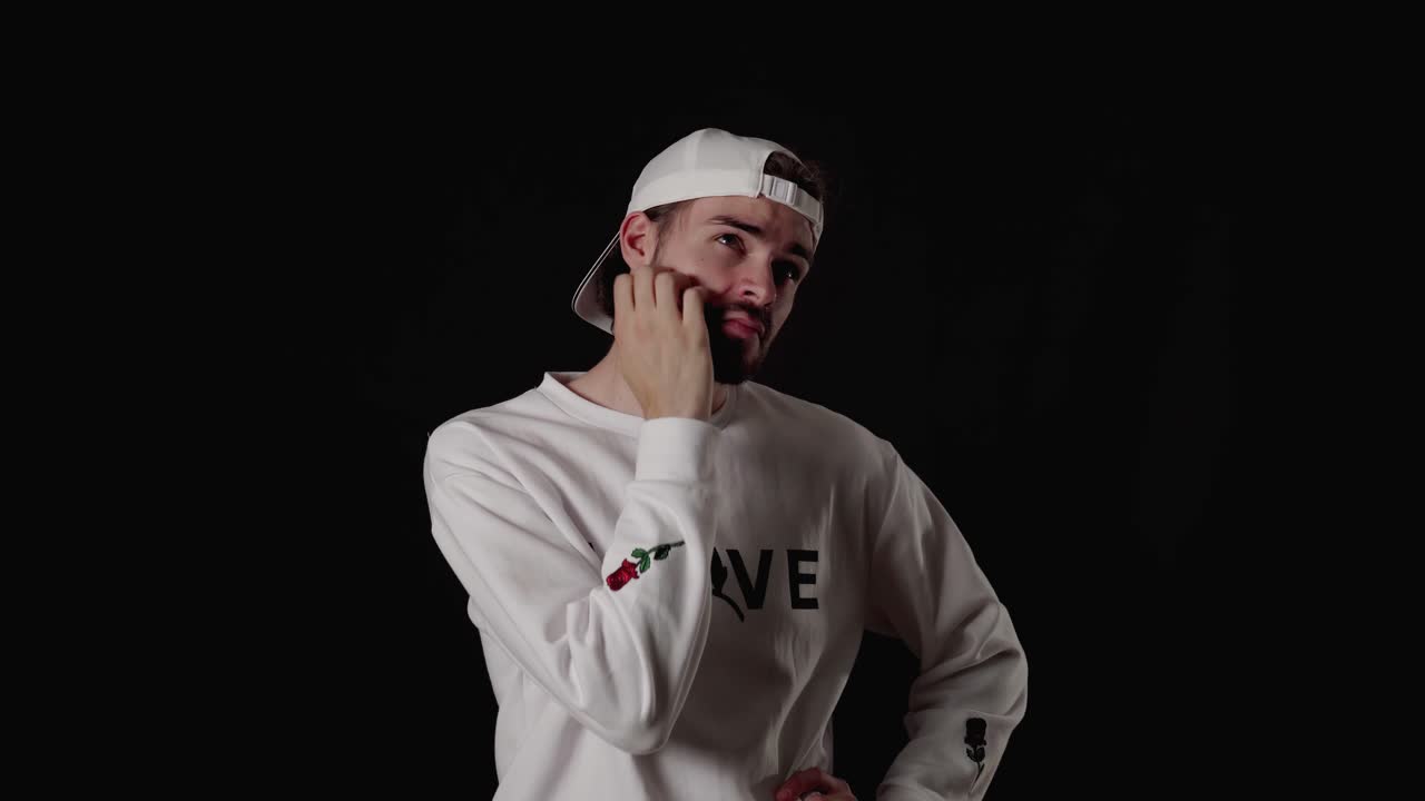 Trendy 20s Man rubbing chin and thinking, wide, black background