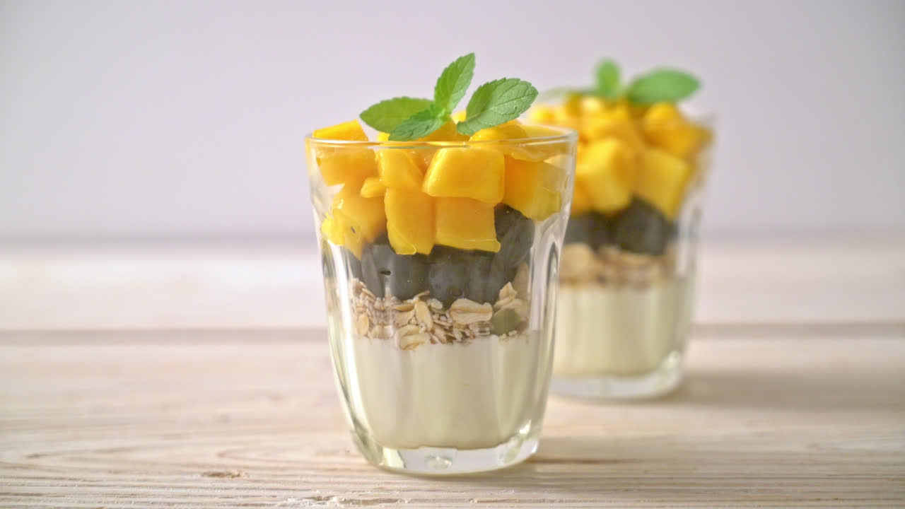 mango fresco casero y arándanos frescos con yogur y granola - estilo de comida saludable