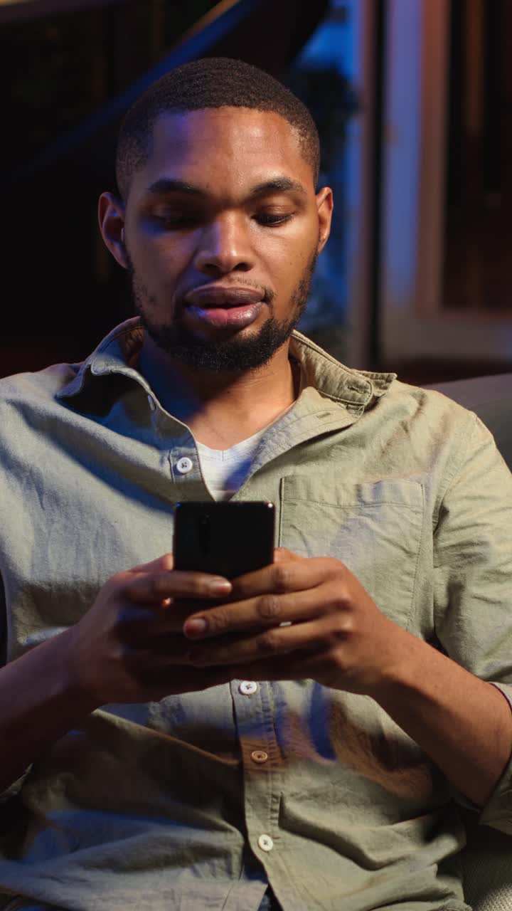 Video verticale. Giovane ragazzo afroamericano che scrive ai suoi amici tramite app di messaggistica sui social media.