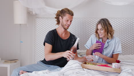 pareja bebiendo champán en la cama para celebrar el cumpleaños o el día de san valentín