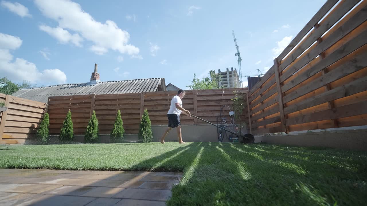 hombre colocando césped en el jardín del patio trasero para la instalación de césped y proyecto de jardinería, centrado en la mejora del hogar y el mantenimiento al aire libre para un césped fresco y verde en un patio residencial