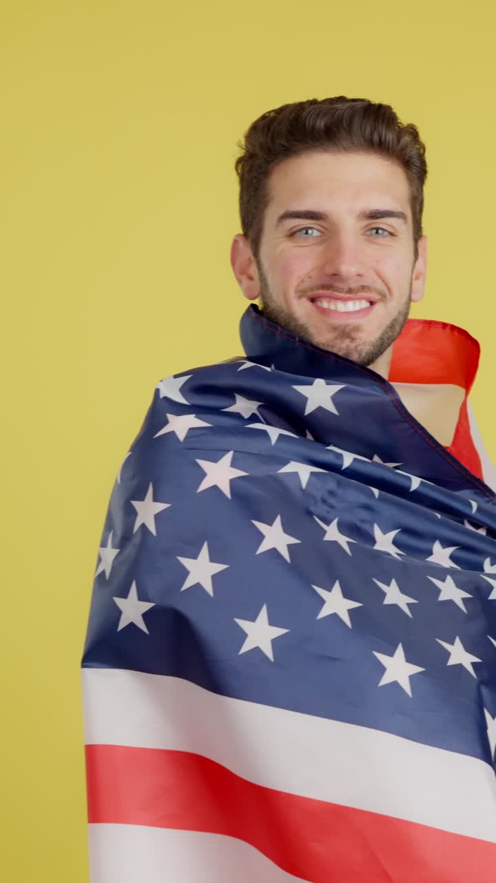 Smiling Man Wrapped in American Flag Against Yellow Background
