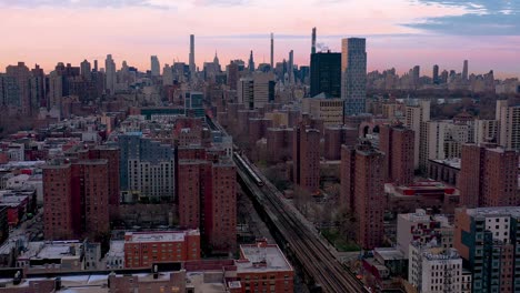 Epic-aerial-stationary-shot-of-commuter-train-heading-through-a-housing-project-in-Harlem-New-York-City-down-into-Midtown-Manhattan