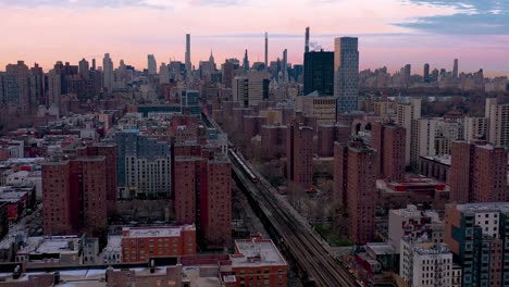 Toma-Estacionaria-Aérea-épica-Del-Tren-De-Cercanías-Que-Se-Dirige-A-Través-De-Un-Proyecto-De-Vivienda-En-Harlem,-Ciudad-De-Nueva-York,-Hacia-El-Centro-De-Manhattan