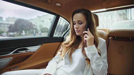 apathetic business lady talking on mobile phone in salon of modern car.