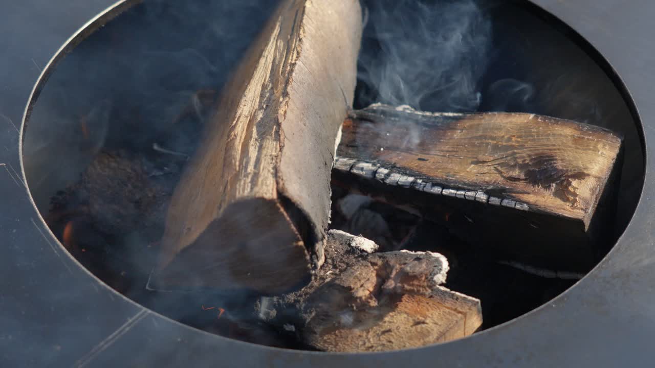 Slow motion shot of wood logs burning in the centre of a wood fired bbq
