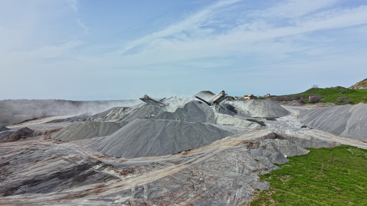 Lokasi tambang granit menunjukkan tumpukan batu besar yang sedang disiapkan untuk diproses pada hari yang cerah.