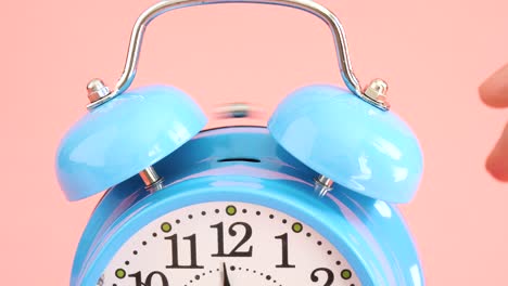 horario de despertador azul aislado en fondo rosado, cámara lenta.