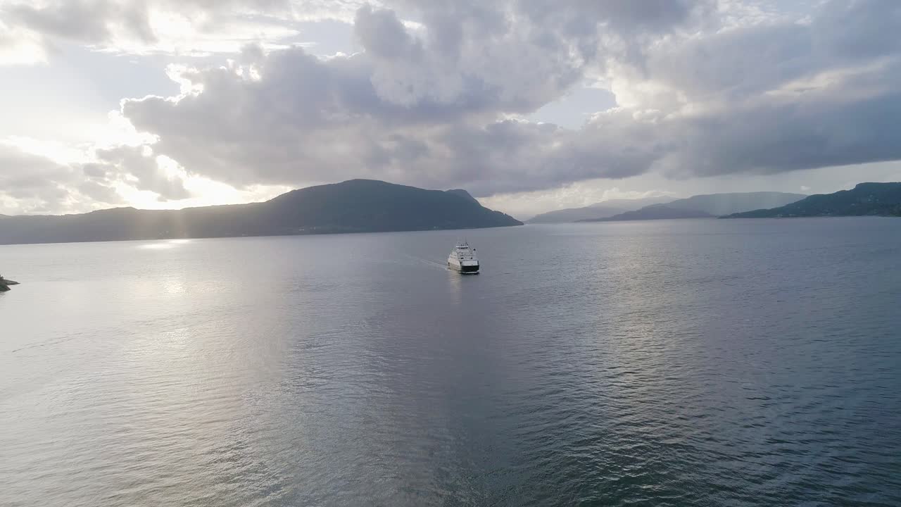 멋진 반사와 함께 일몰 동안 피요르드를 건너는 노르웨이 페리의 공중 슬로모 와이드 샷