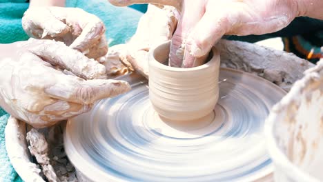 man and woman potter's hands work with clay on a potter's wheel