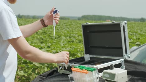 laboratory worker holding professional glassware and testing plant sprouts before harvest in the field.