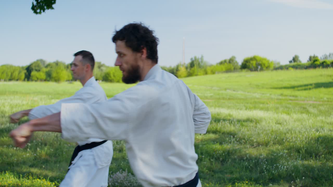 Due uomini che praticano karate all'aperto nella natura
