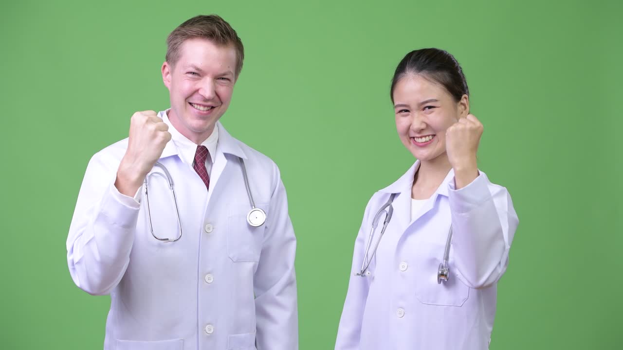 Multi-ethnic couple doctors with fist raised together