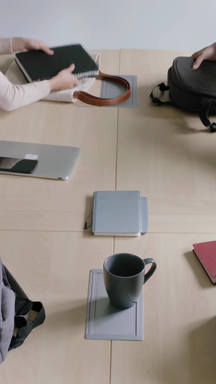 Vertical video: Packing pair at table after meeting, in work clothes, closing laptop, lifting tote