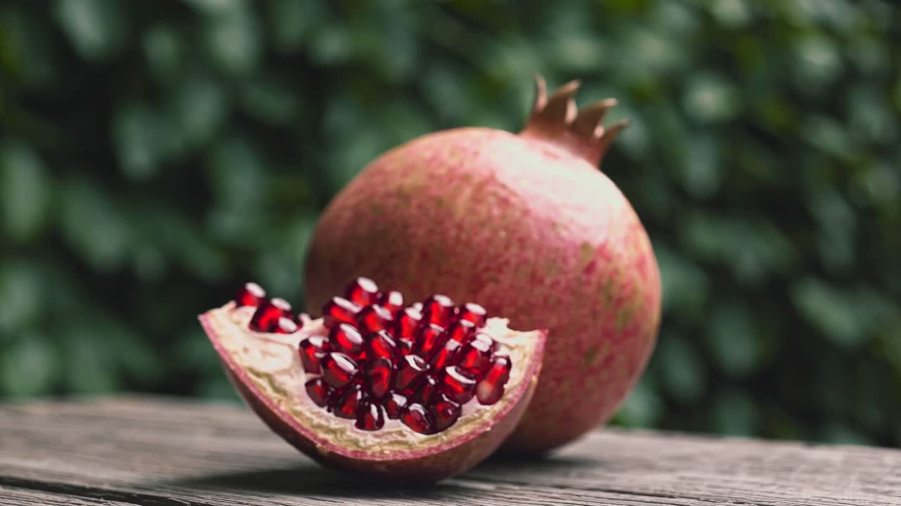 Nærbillede af en video med et granatæble på en træoverflade, hvor kernerne er synlige